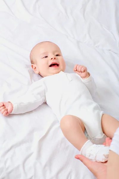 Bebê pequeno feliz sorrindo enquanto deitado na cama — Fotografia de Stock