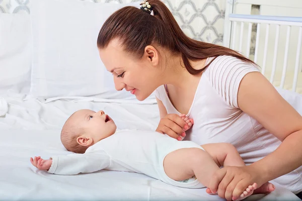 Ragazzina felice sdraiata vicino alla madre su un letto bianco. Ragazze guarda — Foto Stock