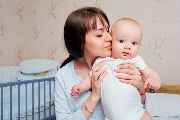 Closeup.Mom pajamas tenderly kisses the baby boy on the bed in t — Stock Photo, Image