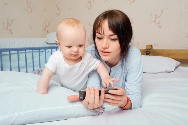 Bébé garçon mignon avec une belle mère brune sur le lit dans le — Photo