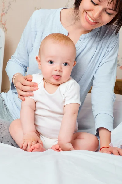 Baby sticking his tongue out. Portrait of funny baby with mother — Stock Photo, Image