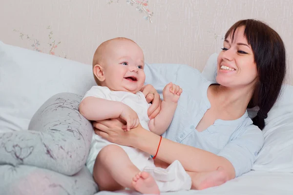 Feliz bebé juega con mamá en pijama en la cama, riendo y sm — Foto de Stock