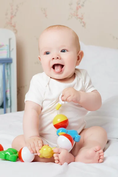 Söt leende baby skrattar och leende med en leksak i handen. L — Stockfoto