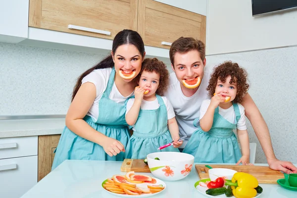 Jumelles fille avec ses parents dans la cuisine manger des petits pains. Un heureux — Photo