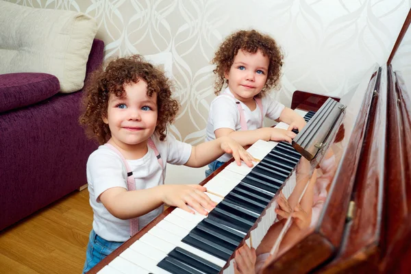 Due gemelli divertenti che suonano il pianoforte insieme, sorridendo, ridendo. Ch — Foto Stock