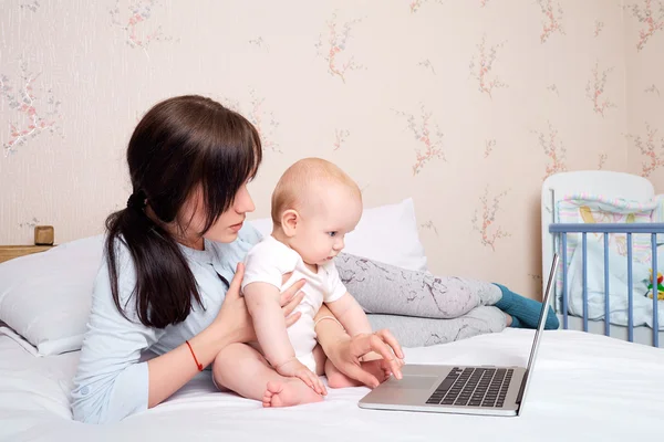 Matka z dzieckiem na łóżku patrząc na laptopa z entuzjazmem — Zdjęcie stockowe