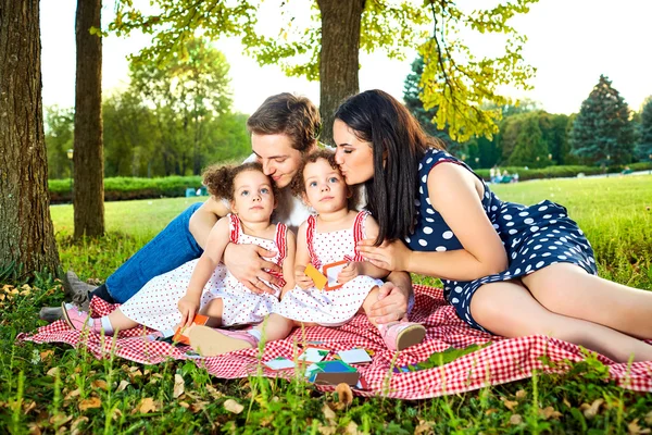 Junge Familie liest ein Buch im Freien liegend auf dem Gras in der p — Stockfoto