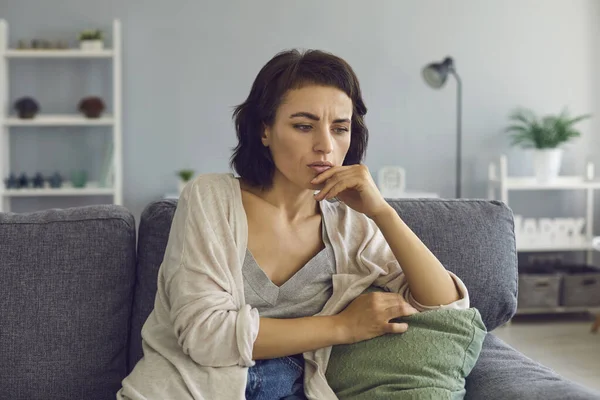 Young woman feeling frustrated touching chin during online meeting — Stock Photo, Image