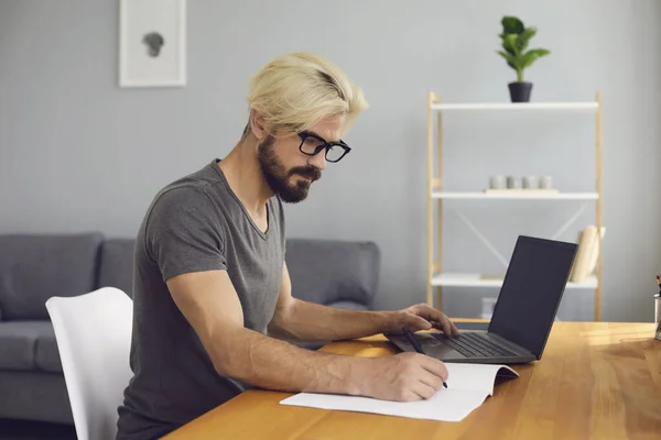 Mladý muž s notebookem pracuje on-line v domácí kanceláři, přičemž vzdělávací kurz nebo komunikaci prostřednictvím video chatu — Stock fotografie