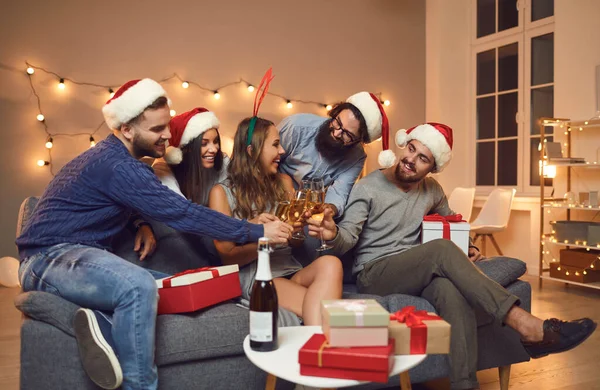 Amigos sentados en el sofá, tintineando vasos y deseándose Feliz Navidad y Feliz Año Nuevo — Foto de Stock