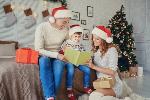 Famille lisant un bookin une maison avec un arbre de Noël. — Photo