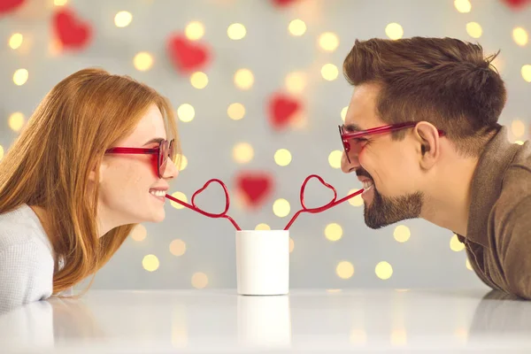 Nettes glückliches junges Paar schlürft am Valentinstag einen Drink aus einer Tasse — Stockfoto