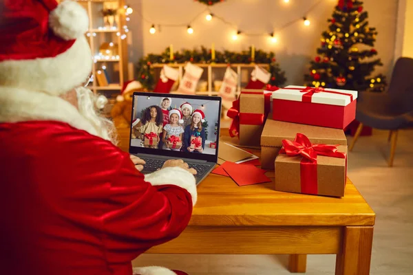 Father Christmas sitting at laptop computer and video calling happy diverse children — Stock Photo, Image