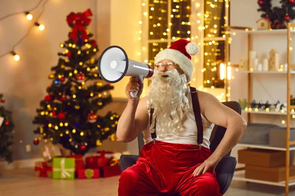 산타는 대형 새해와 크리스마스 판매 시작을 발표하는 메가폰과 함께 안락 의자에 앉아 — 스톡 사진