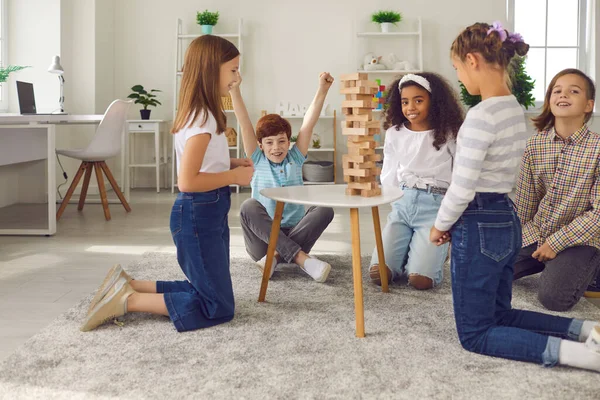 Group of happy kids playing wood block tower stacking game at home or in after school leisure club — Stock Photo, Image