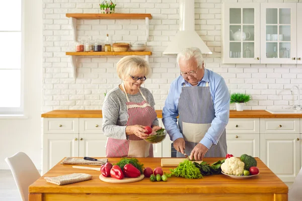 在他们现代化的厨房里，快乐的大四夫妻一起做着健康的沙拉 — 图库照片