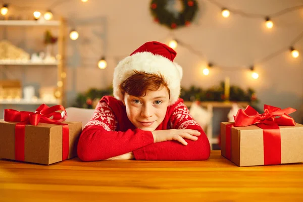 Mutlu bir çocuğun portresi Noel hediyelerinin arasında ellerini masaya yaslıyor.. — Stok fotoğraf