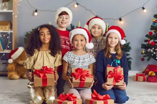 Porträt einer Gruppe fröhlich lächelnder internationaler Kinder mit Weihnachtsgeschenken in einem Raum. — Stockfoto