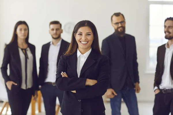 Šťastný usměvavý vedoucí ženské společnosti s týmem zaměstnanců stojící v pozadí — Stock fotografie