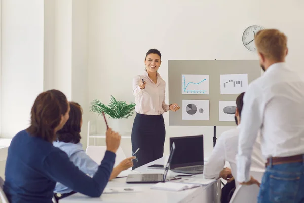 Mujer joven feliz respondiendo a la pregunta mientras que da la presentación en reunión corporativa —  Fotos de Stock