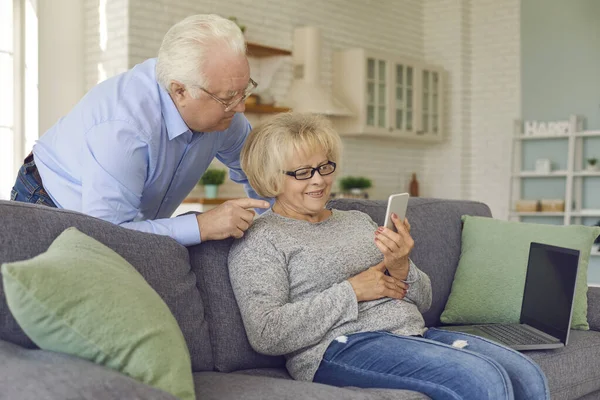 Sorridente coppia matura odering o comunicare su smartphone a casa insieme — Foto Stock