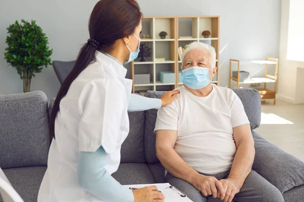 Dokter pendukung yang ramah mengunjungi pasien pria senior selama pandemi coronavirus. — Stok Foto
