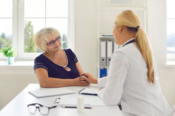 Ärztin hält die Hand ihrer betagten Patientin in einem Krankenhauszimmer als Zeichen der Unterstützung. — Stockfoto