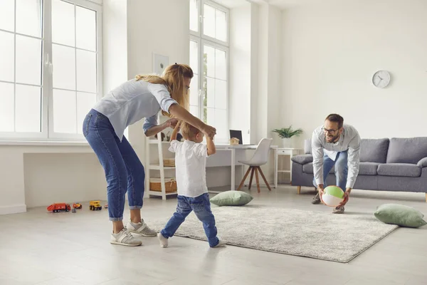 Ibu dan ayah yang bahagia dengan anak kecil menghabiskan waktu di rumah dan bermain dengan bola tiup — Stok Foto
