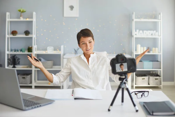 Vídeo de gravação vlogger feminino confiante na câmera sentada em sua mesa no aconchegante escritório em casa — Fotografia de Stock