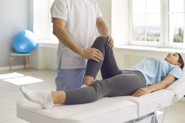 Modern tıp merkezindeki fizyoterapist bacak problemi olan genç bir kadınla çalışıyor.
