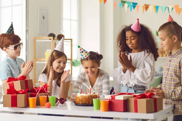 Lycklig flicka gör sin födelsedag önskar innan blåsa ljus på tårta under festen med vänner — Stockfoto