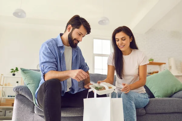 Young smiling couple unpacking online healthy boxed food order for dinner delivery