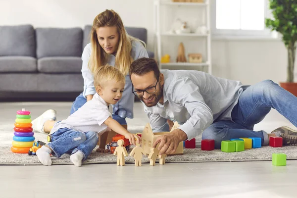 Gelukkig gezin spelen met speelgoed op de vloer van hun woonkamer, genieten van quality time thuis — Stockfoto