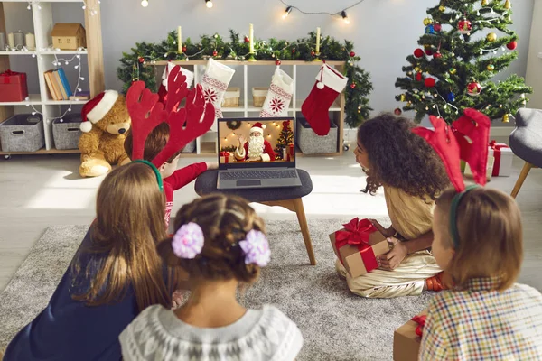 Group of kids gathering around laptop and video calling Santa Claus to thank him for presents — Stock Photo, Image