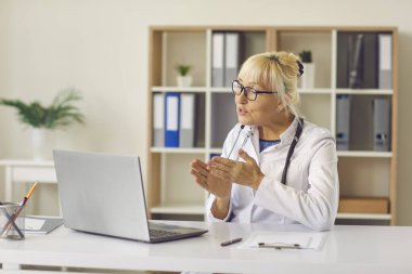 Üst düzey kadın aile doktoru hastasıyla çevrimiçi danışmanlık yapmak için dizüstü bilgisayar kullanıyor..