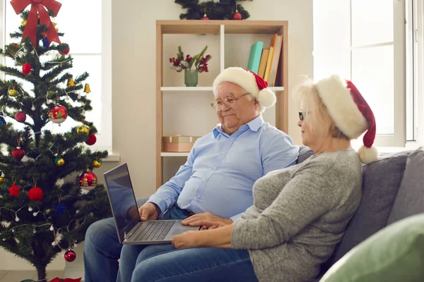 Vue latérale de heureux couple de personnes âgées à l'aide d'un ordinateur portable regarder des films de Noël préférés. — Photo