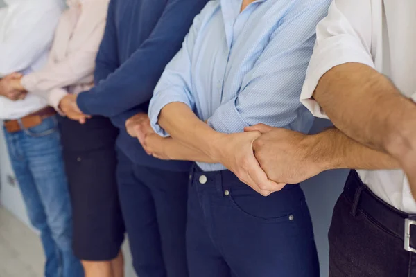Überkreuzte Hände von Geschäftsleuten, die auf der Seite stehend die Hände von Partnern halten, die Teamarbeit ausdrücken — Stockfoto