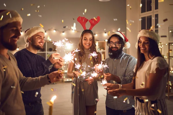 Amigos sonrientes con bengalas deseándose unas a otras Feliz Navidad y Feliz Año Nuevo en casa —  Fotos de Stock