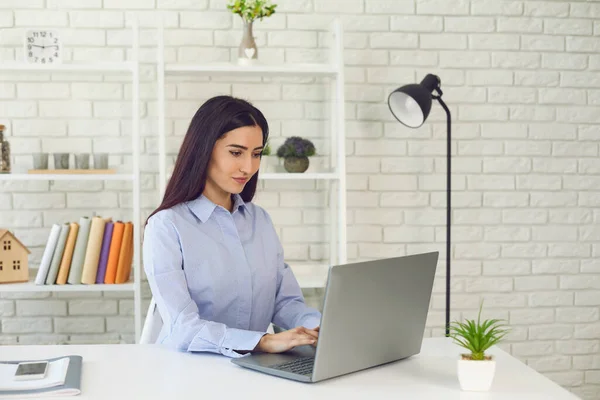 Junge Brünette benutzt Laptop im Büro — Stockfoto