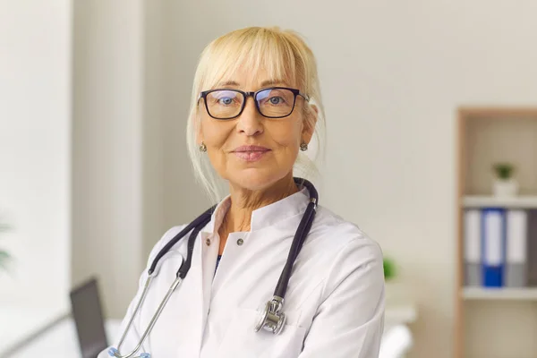 Close up portrait of an experienced friendly senior doctor woman looking at camera. — Stock Photo, Image