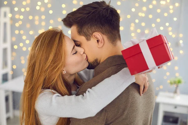 Oldalnézet egy gyönyörű fiatal nő csókolgatja a férjét hálából az ajándékért.. — Stock Fotó