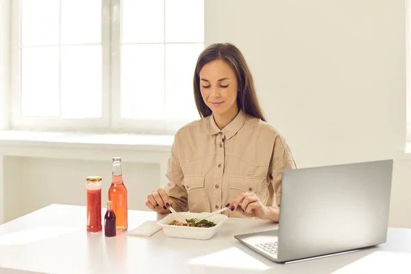 Jovem trabalhadora do escritório comendo comida durante a pausa para o almoço em casa ou no escritório. — Fotografia de Stock