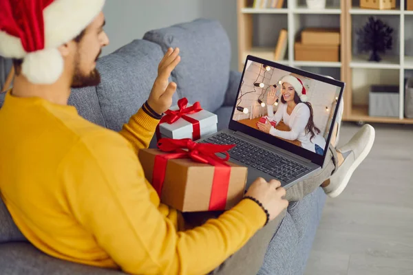 Genç adam dizüstü bilgisayar ve video ile koltukta oturuyor ve Noel tatilinde kız arkadaşını arıyor. — Stok fotoğraf