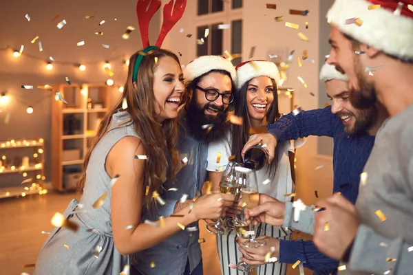 Feliz sorrindo amigos derramando champanhe de garrafa e celebrando o Natal em casa — Fotografia de Stock