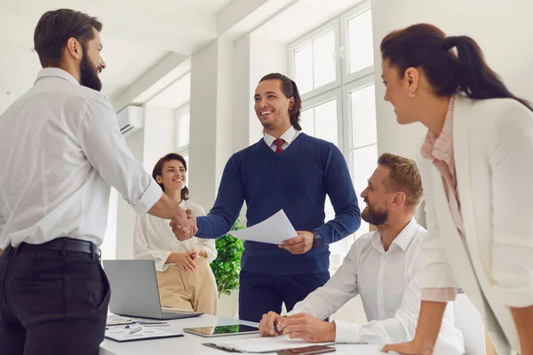 Freundlicher Teammanager beim Händeschütteln mit glücklichen Mitarbeitern während eines Arbeitstreffens — Stockfoto