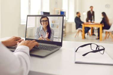İş adamı dizüstü bilgisayardan video görüşmesi yapıyor ve çalışan ya da müşteriyle iletişim kuruyor.
