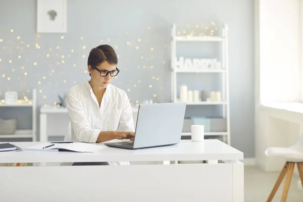 Obchodní dáma v brýlích sedí doma a pracuje na notebooku on-line — Stock fotografie