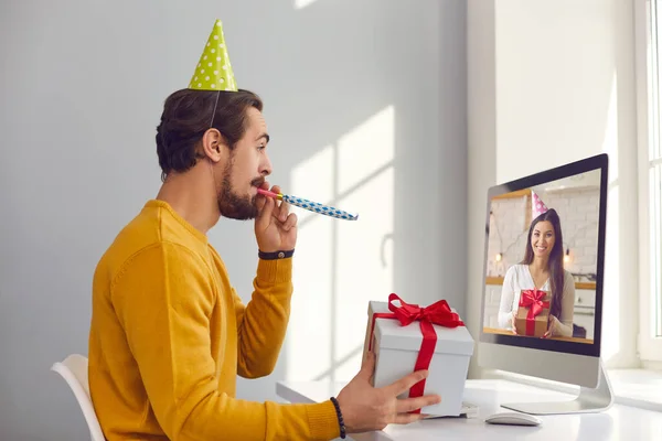 Happy young man sitting at computer and having virtual party with his friend or girlfriend — Stock Photo, Image