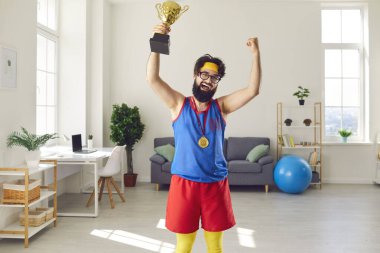 Neşeli, sakallı, vahşi bir sporcu. Çok renkli spor kıyafetleri içinde. Elinde birincilik ödülü var.