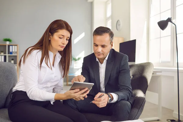 Uomini e donne impiegati seduti con tablet digitale e che controllano i flussi di lavoro in ufficio. — Foto Stock